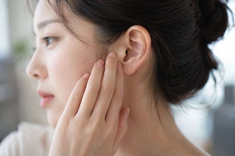 귀 앞을 짚고 있는 여성